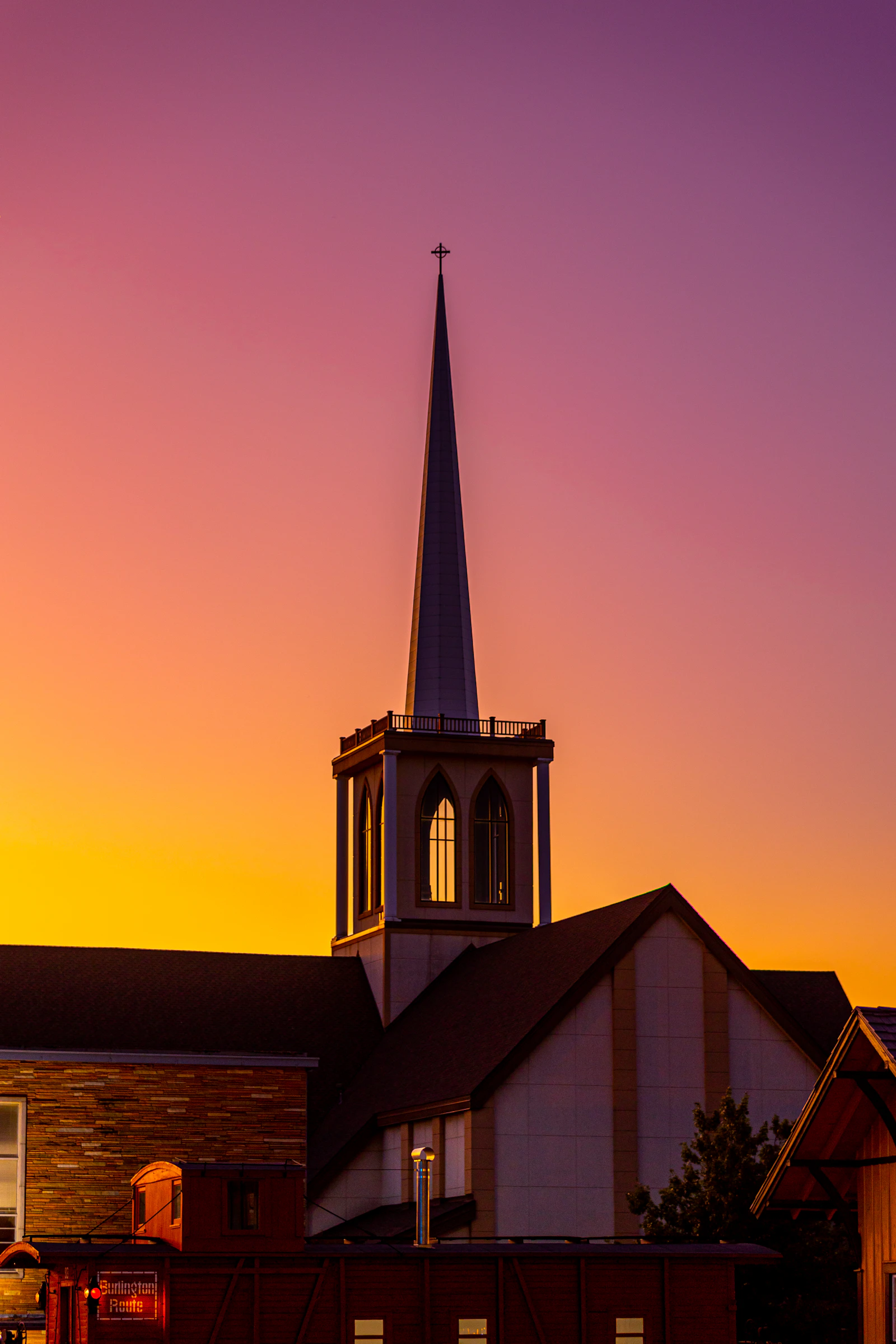 Church steeple silhouetted against a vivid sunset