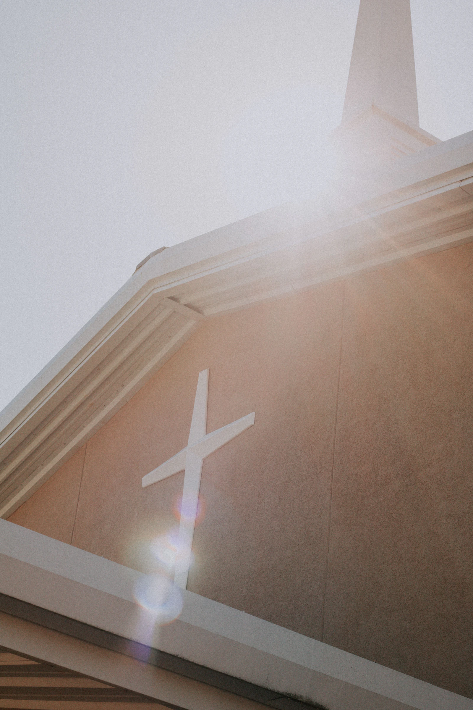 Sunlight shining across a cross on a church wall